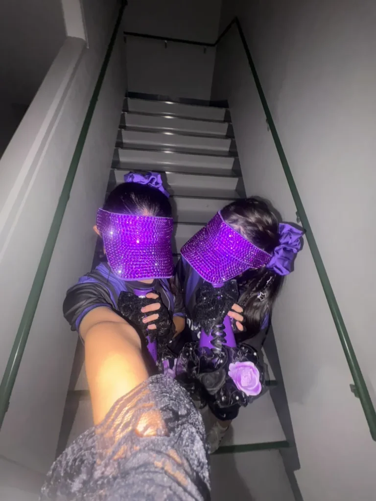 紫色のストーンでキラキラにデコられた紫色のサンバイザーをつけた女子高生二人の写真